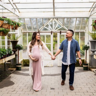 Expecting couple holding hands in the beautiful Christianson Nursery in Mount Vernon, Wa.