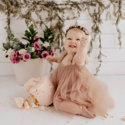 One year old girl smiling and doing a cake smash in Seattle studio.