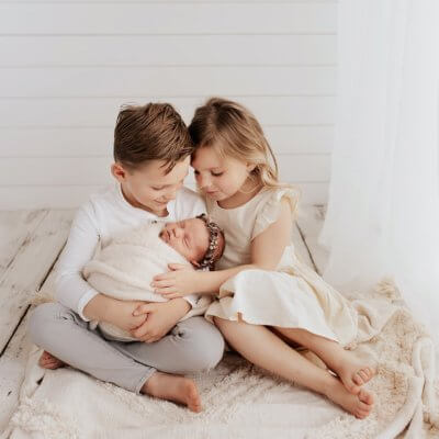Sibling holding their new baby sister in a Seattle studio newborn session.